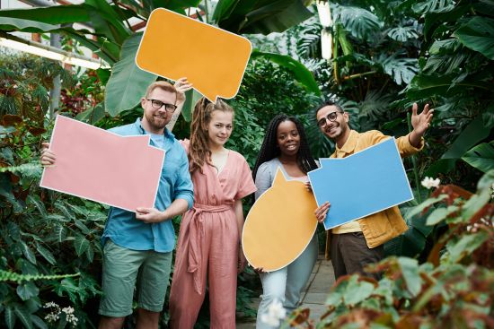 Gruppe junger Menschen mit Sprechblasen-Schildern ©pexels